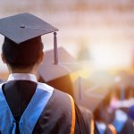 Rear View Of University Graduates Wearing Graduation Gown And Cap